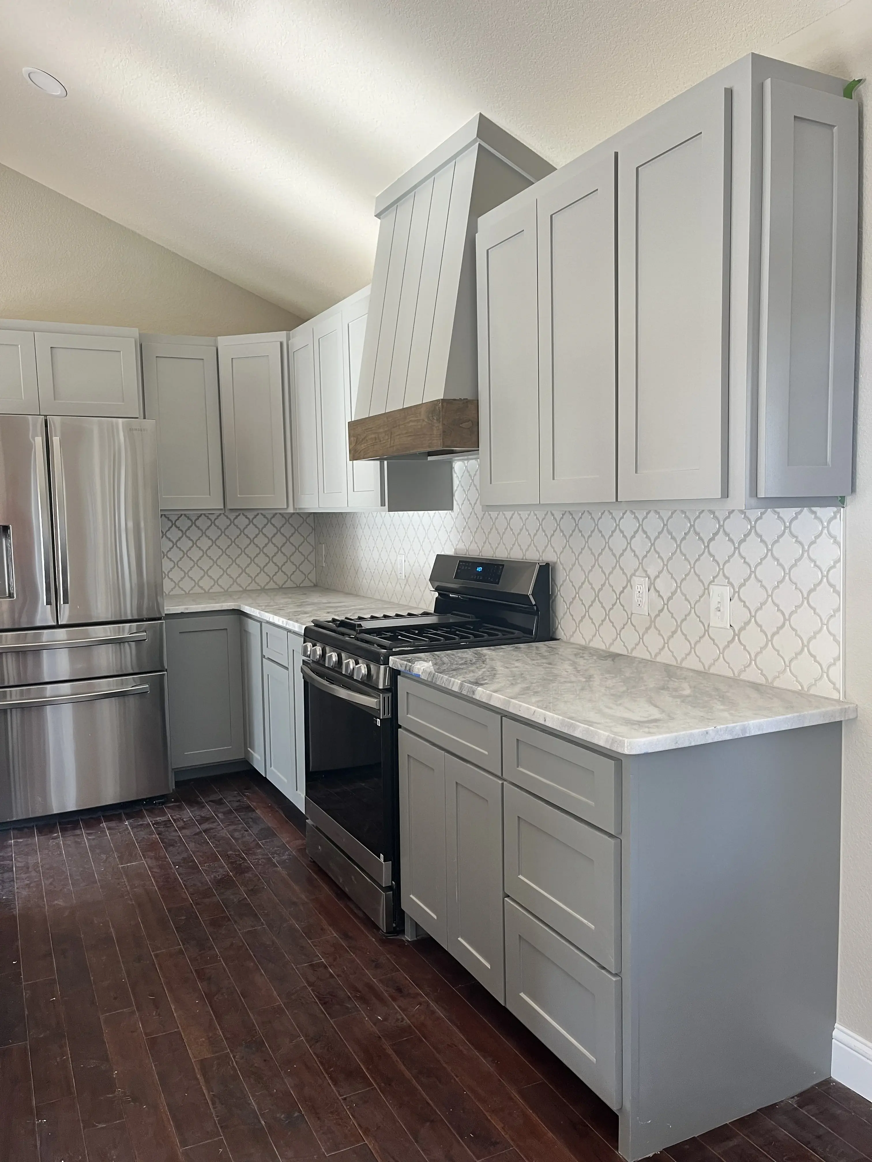 Gray shaker kitchen with custom wood-trimmed range hood
