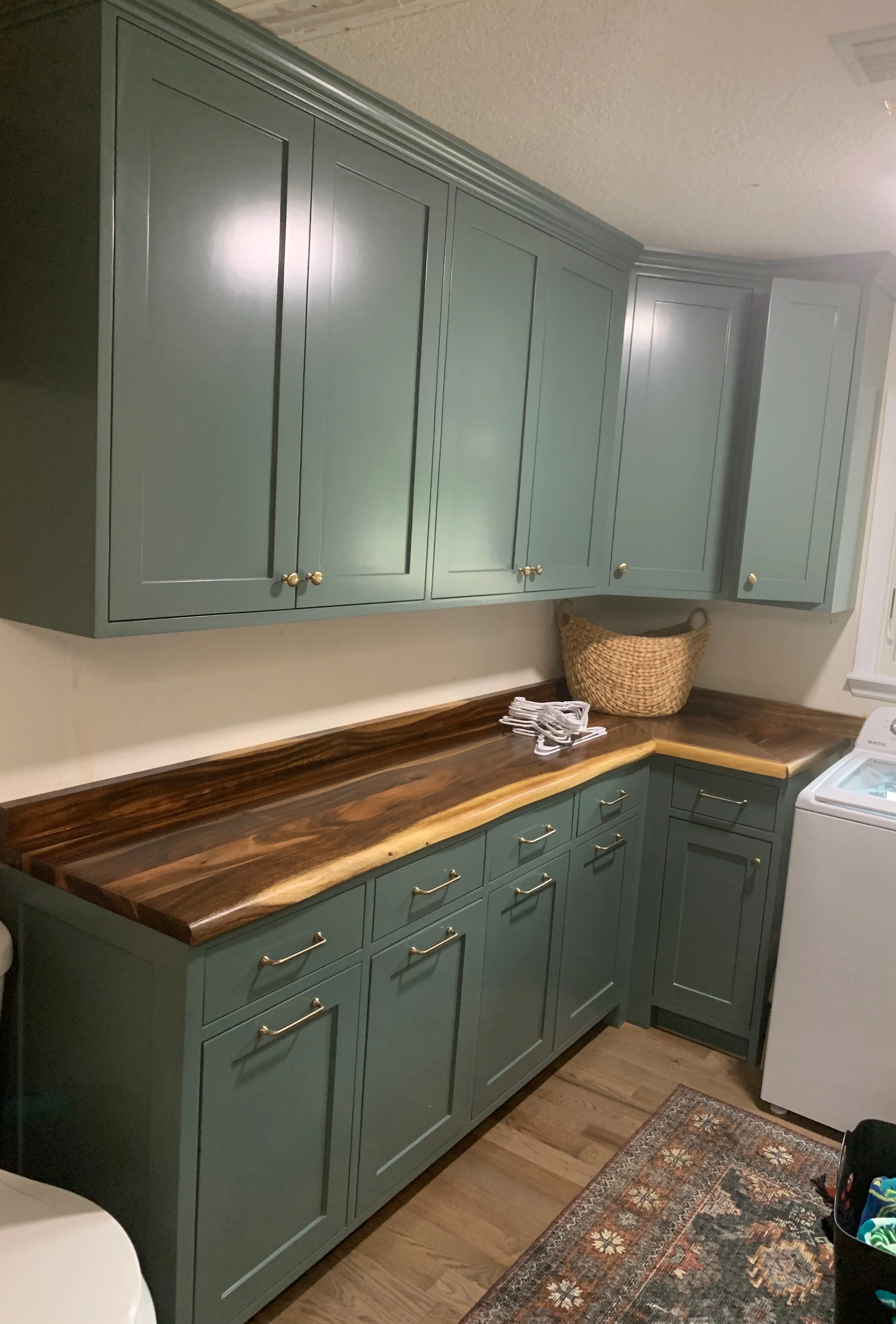 Sage green laundry room cabinets with live edge walnut counter