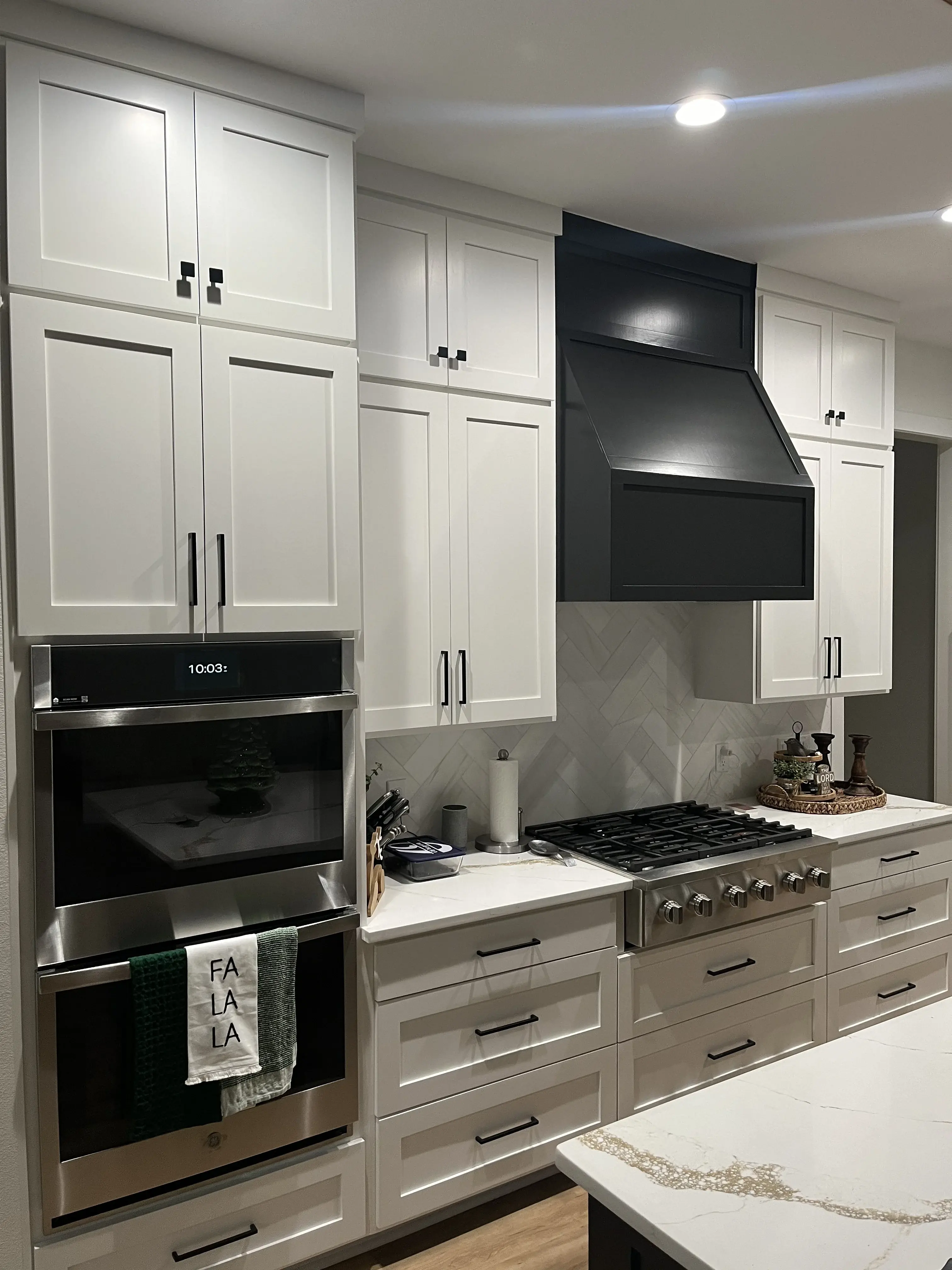 White inset kitchen with black wood hood and herringbone backsplash
